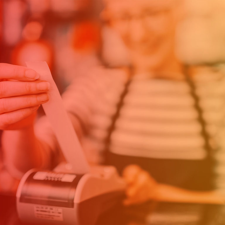 Close up of smiling Caucasian female worker with short blonde hair and eyeglasses using cash register while standing in bicycle store.